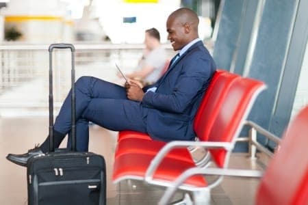 Voyageur en costume attendant son vol, valise à côté de lui